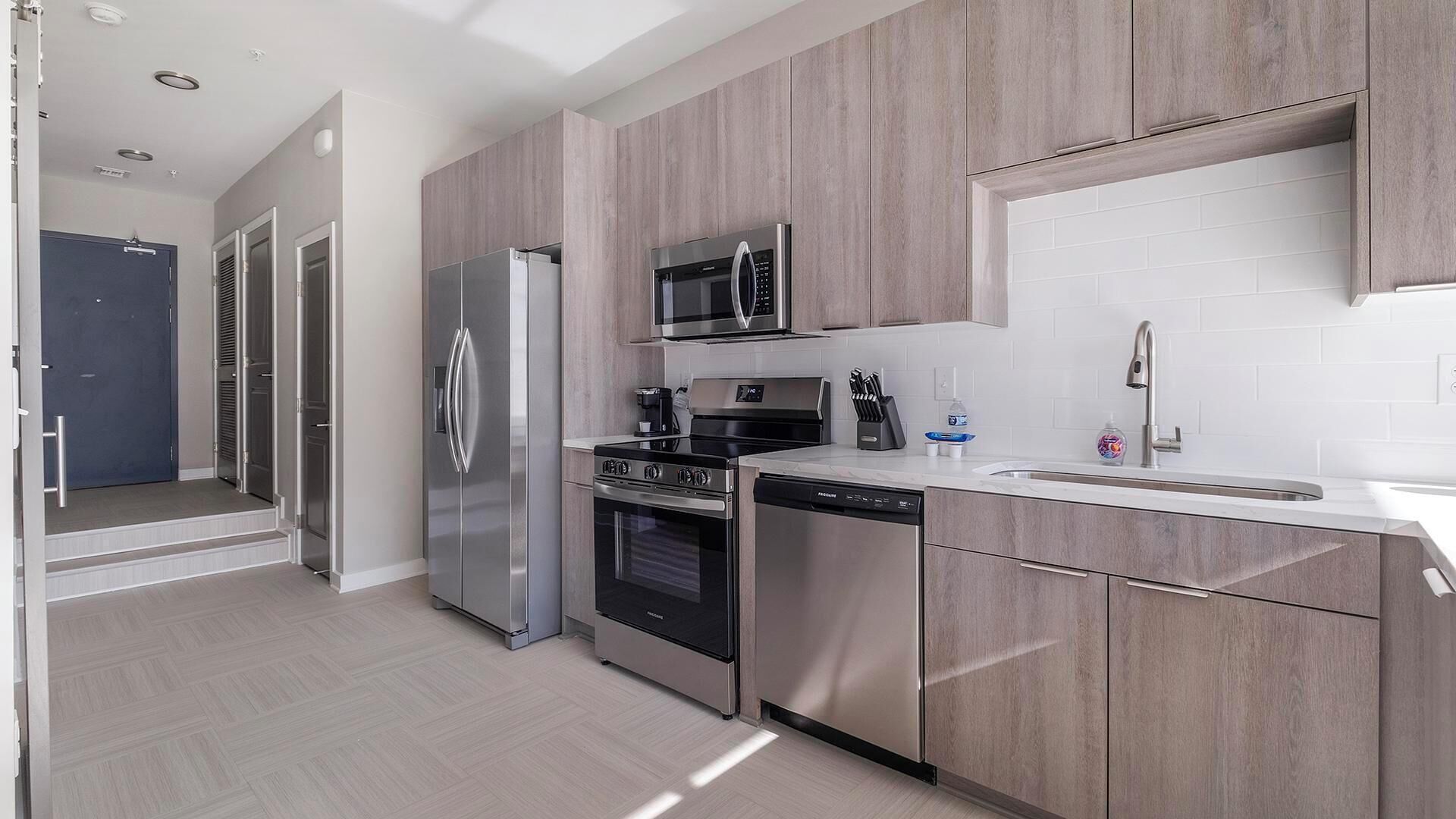 Una cocina moderna con electrodomésticos de acero inoxidable, lavavajillas y microondas.
