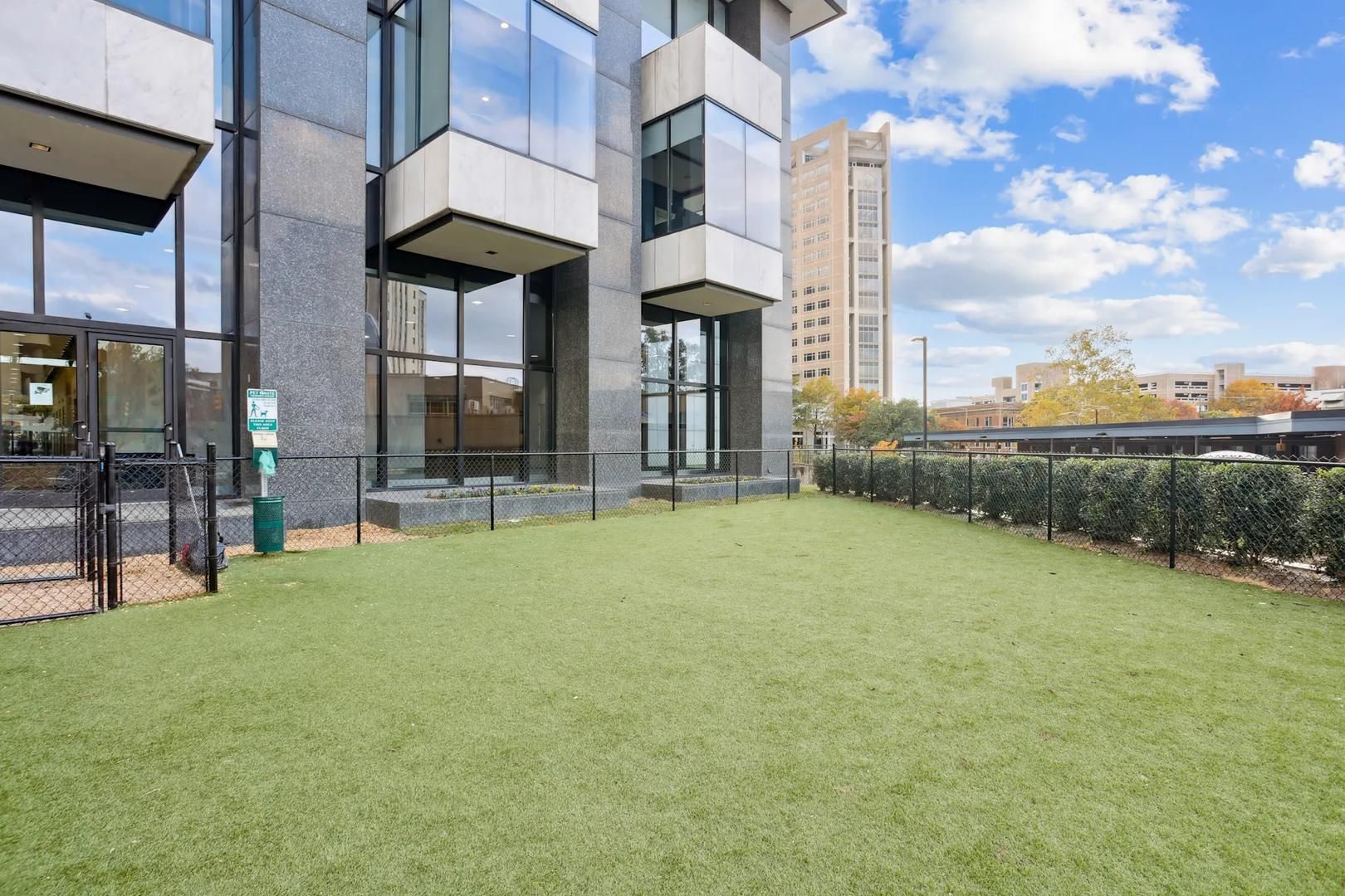 Un edificio moderno con techo plano, amplias ventanas y un patio ajardinado.