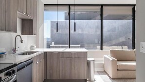 Een moderne keuken met een inbouwfornuis, een spoelbak en een raam met uitzicht op een gebouw.