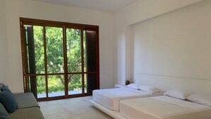 Quarto com uma grande porta de vidro deslizante que dá para uma varanda, uma cama, um sofá e uma pequena mesa.