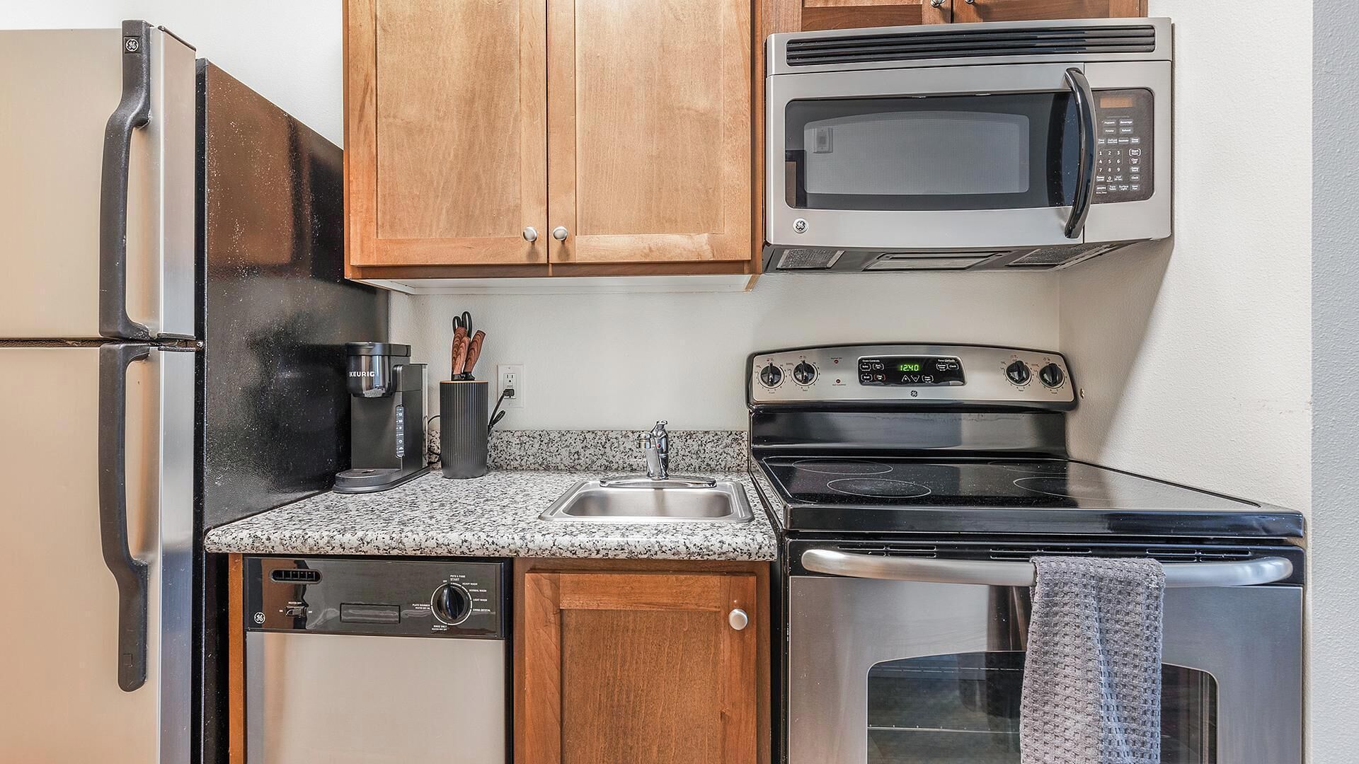 A compact kitchen with a refrigerator, microwave, stove, and dishwasher.