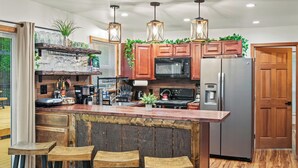 Una cocina moderna con armarios de madera, un refrigerador de acero inoxidable, un horno empotrado y una zona de bar con taburetes.