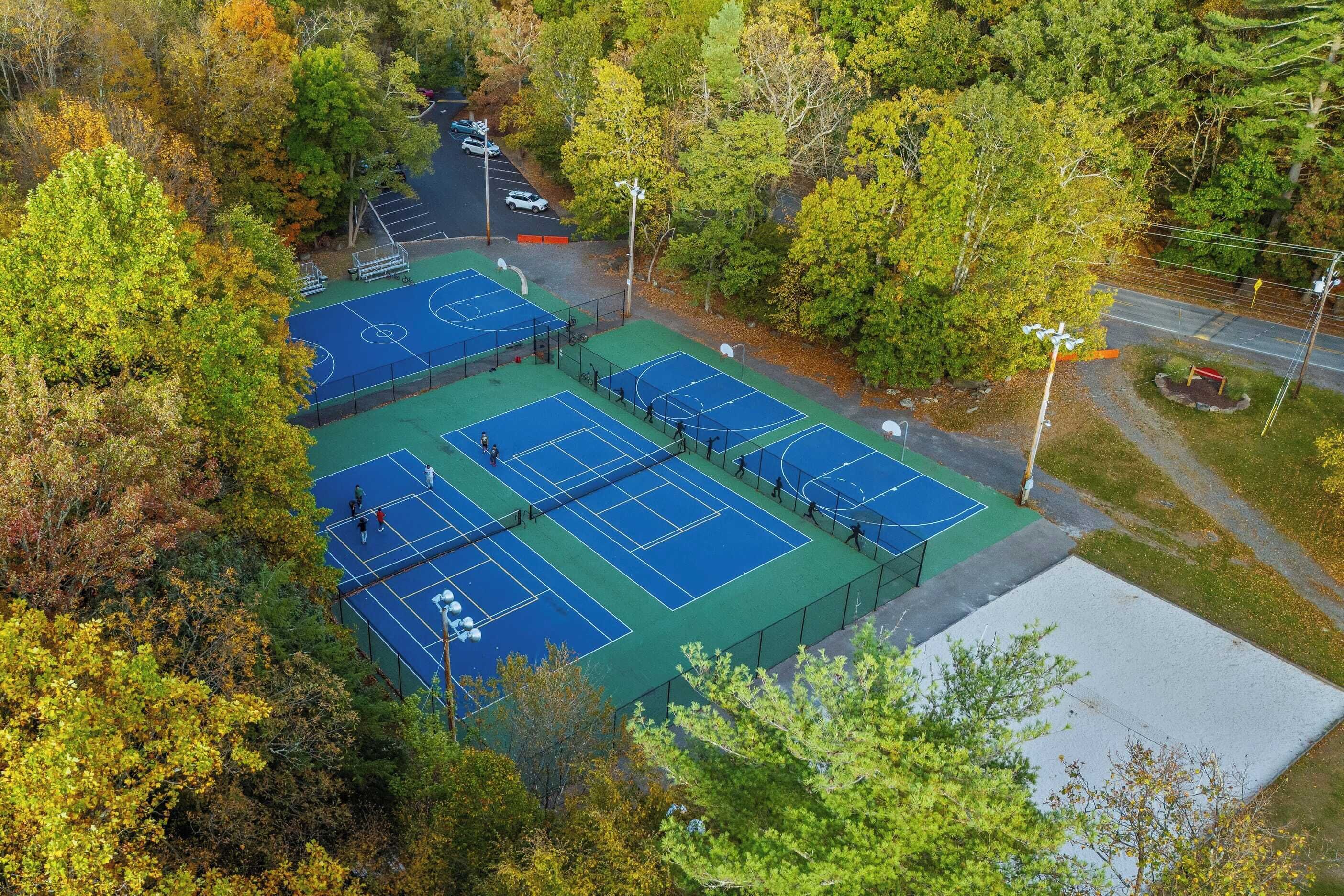 An aerial view of a tennis court complex surrounded by trees.
