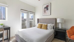 A modern hotel room with a large bed, a desk, a chair, and a nightstand. - Landing | Incredible Studio, Courtyard, Gym (Portland)