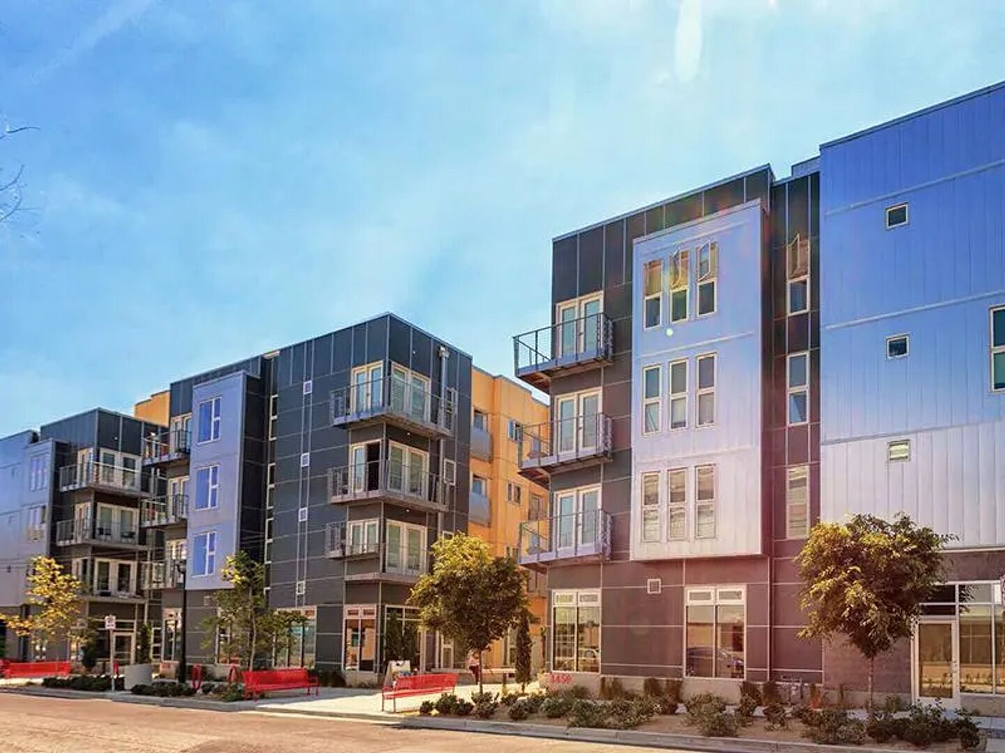 Un immeuble résidentiel moderne à plusieurs étages, doté de balcons et de grandes fenêtres.