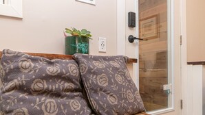 Een houten bank met gestreepte kussens, een groene plant in een vaas en een deur met een houten paneel.