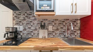 Een moderne keuken met een houten aanrecht, een roestvrijstalen spoelbak en een spatwand met kleurrijke tegels.