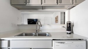 A modern kitchen with a double sink, stainless steel faucet, a coffee maker, and a dishwasher. - Landing | Amazing 2BD, Gym, Pool (Austin)
