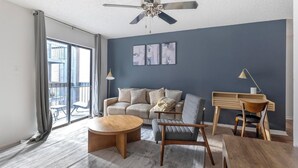 A modern living room with a sofa, armchair, coffee table, and desk.