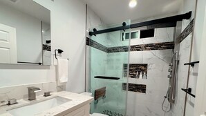 Ein modernes Badezimmer mit einer gläsernen Duschkabine, einer weißen Toilette und einem мрамор Waschbecken.