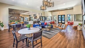 A spacious living area with a dining table, sofas, and a kitchen in the background. - Landing | Amazing 2BD, Rooftop Lounge, Pool (Henderson)