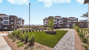 A modern residential complex with multiple apartment buildings, a central lawn, and a paved walkway. - Landing | Amazing 2BD, Rooftop Lounge, Pool (Henderson)
