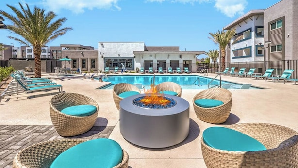 Un espace aménagé au bord de la piscine, avec des chaises longues, un foyer et une piscine.