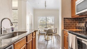 Eine moderne Küche mit Holzausstattung, einer Granit Arbeitsplatte und einem Essbereich mit Tisch und Stühlen.