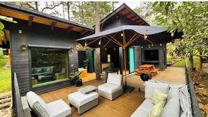 Un espace de vie extérieur moderne, doté d’une terrasse en bois, de mobilier d’extérieur et d’un grand parasol offrant de l’ombre.