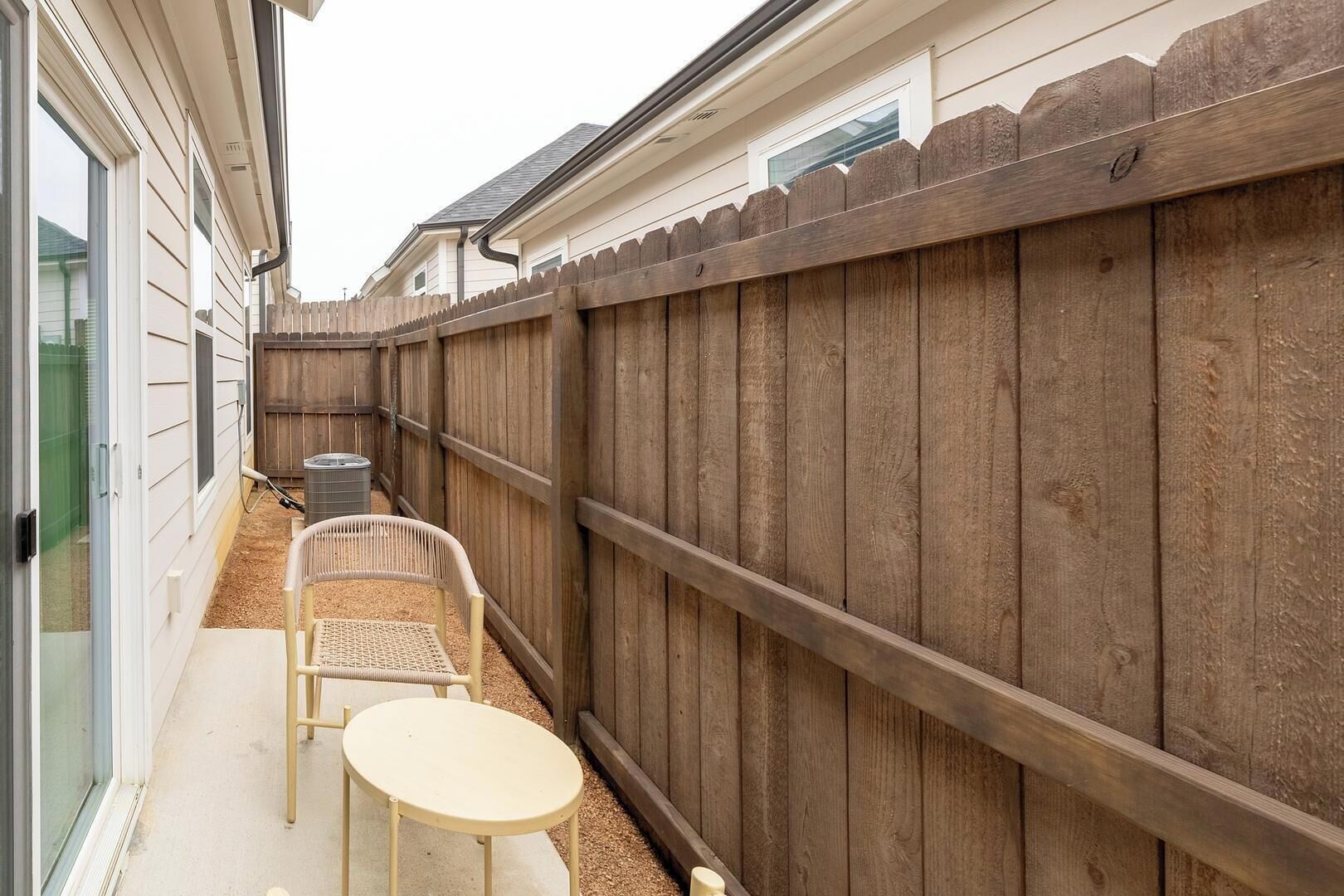Un espace patio agrémenté d’une clôture en bois, d’une table et de deux chaises.