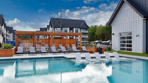 Une piscine avec des chaises longues et une pergola en bois.