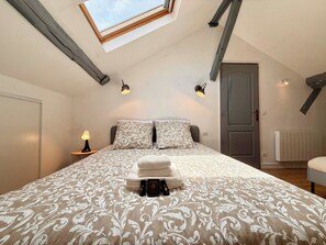 A bedroom with a skylight, a bed with patterned bedding, bedside lamps, a door, and a radiator. - 10' Disneyland & Parking - 9 personnes (Ferrières-en-Brie)