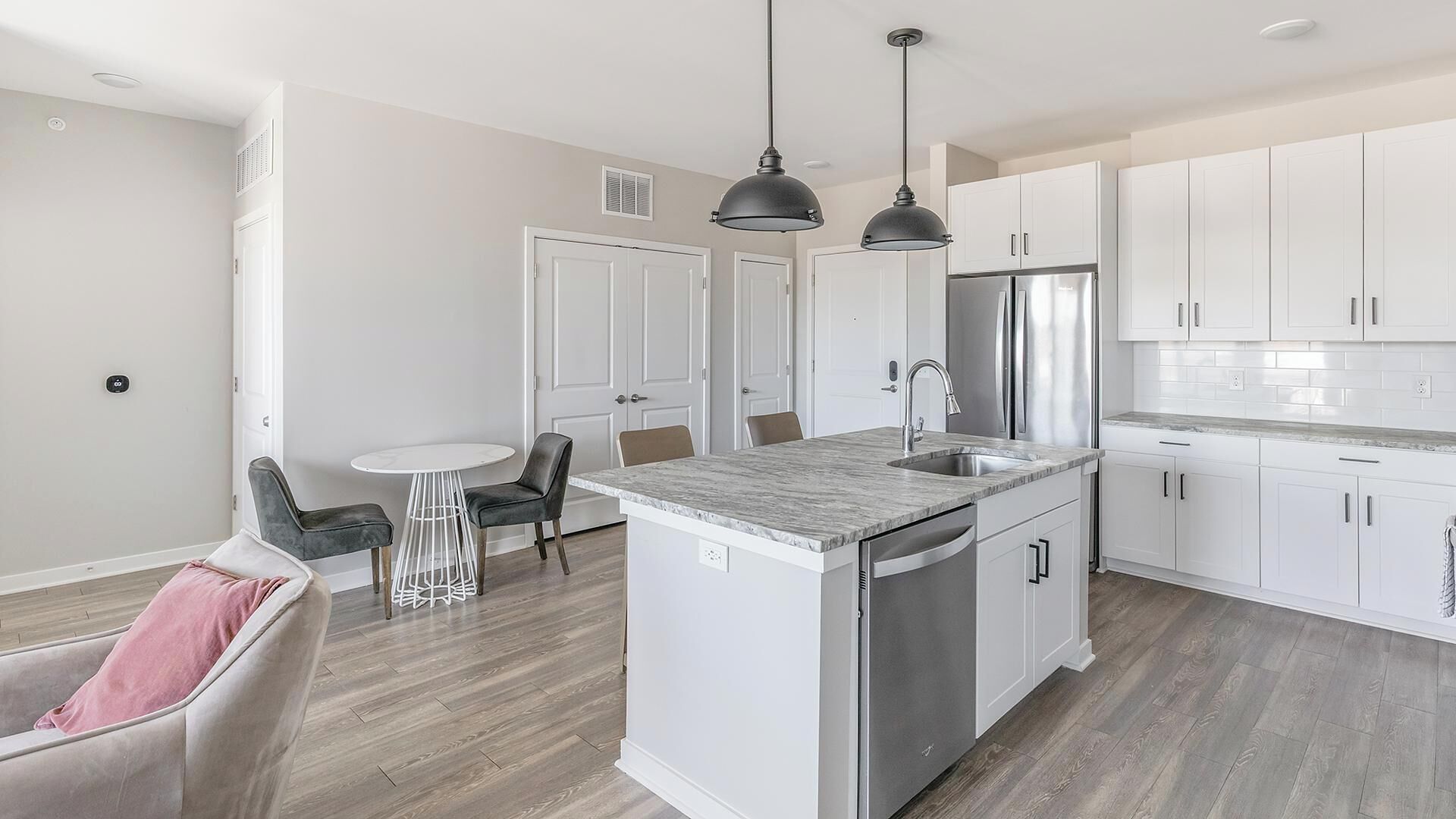 A modern kitchen with white cabinets, a stainless steel refrigerator, and a central island with a sink.