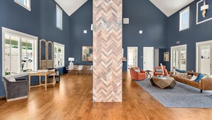Un vaste salon doté d’un haut plafond, de grandes fenêtres et d’un pilier orné d’un motif en chevrons.
