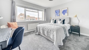 A modern bedroom with a large bed, a desk, and a chair. - Beautiful apartment in Claygate Village (Claygate)