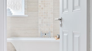 A modern bathroom with a bathtub, a towel rack, and a shower area. - Beautiful apartment in Claygate Village (Claygate)