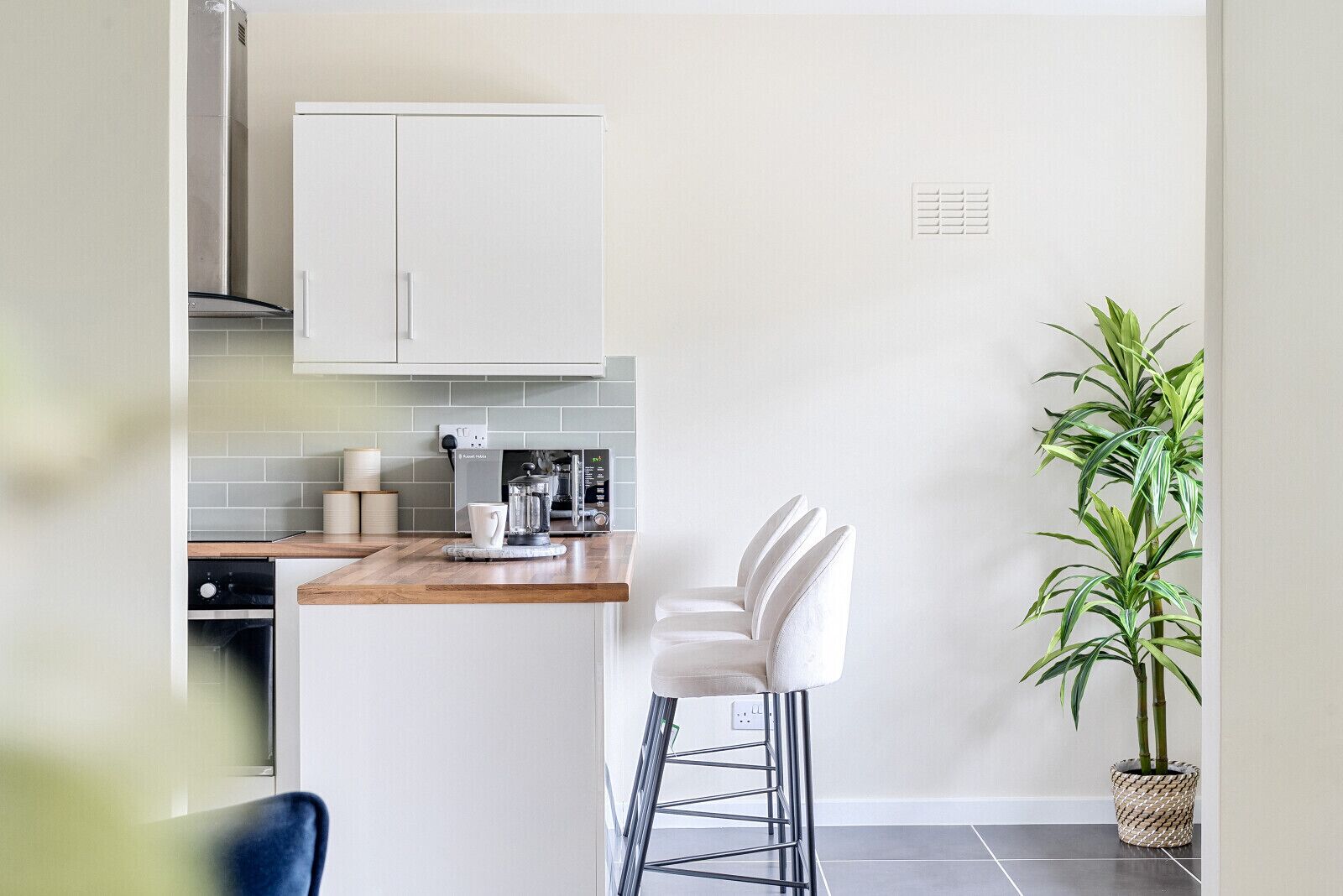 A modern kitchen with white cabinets, a coffee machine, and a bar stool.