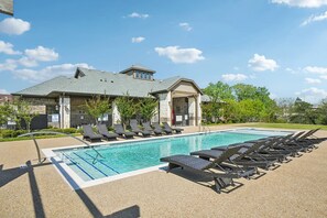 A swimming pool with lounge chairs and a covered area with a roof.