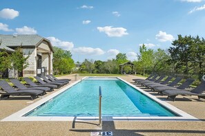 A rectangular swimming pool with a diving board, surrounded by lounge chairs and a gazebo. - Landing | Stylish 1BD, Gym, Pool (Dallas)