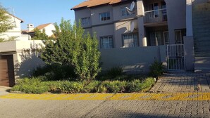 A multi-story residential building with a tiled roof, satellite dishes, and a gated entrance.