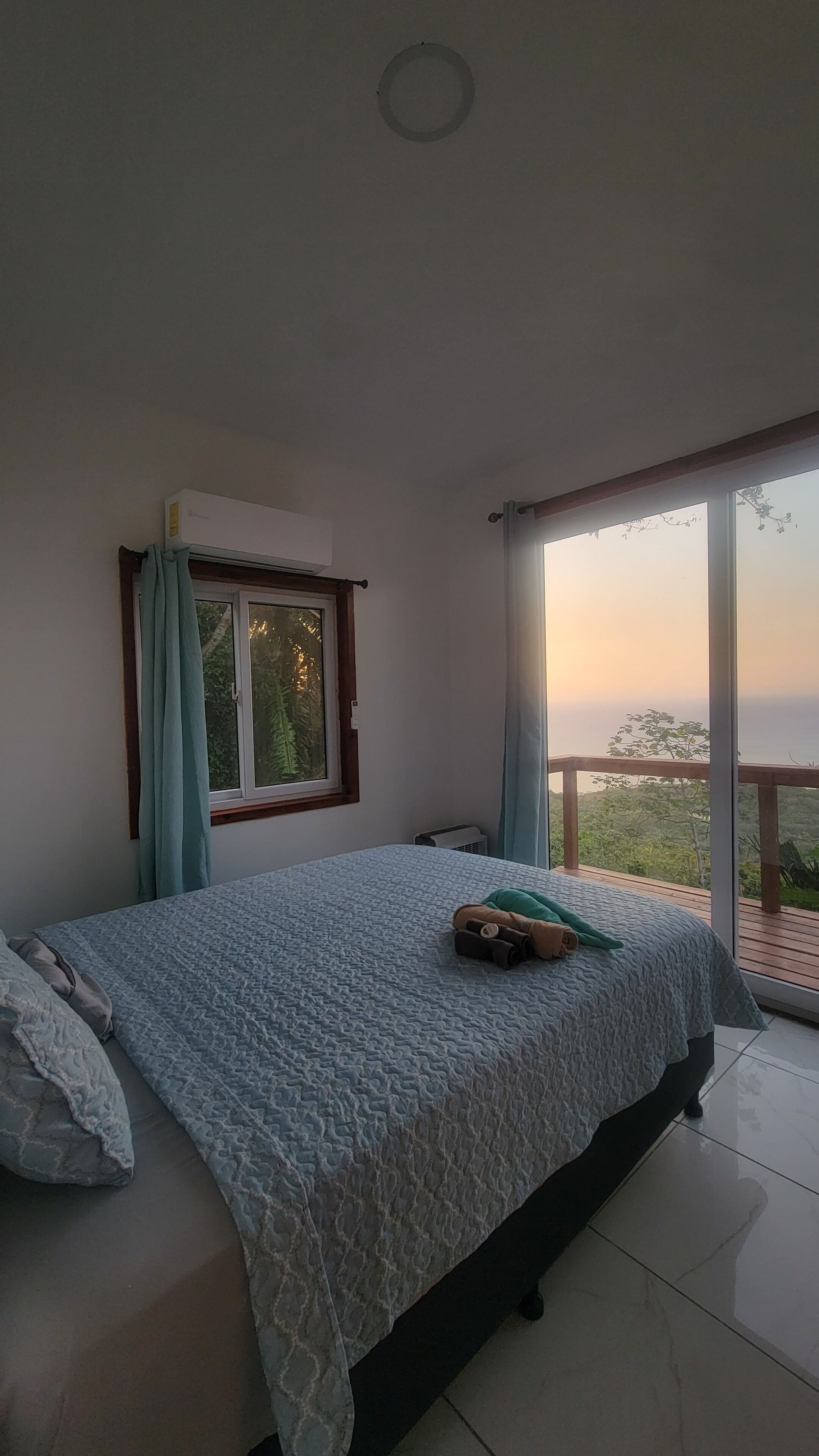 A bedroom with a bed, a window, and a view of the outdoors.
