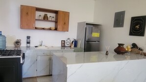 Une cuisine moderne dotée d’un plan de travail en marbre, d’une cuisinière encastrée et d’un réfrigérateur en acier inoxydable.