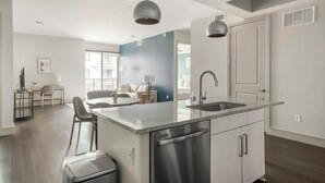 Una cocina moderna con una isla central, electrodomésticos de acero inoxidable e iluminación colgante.
