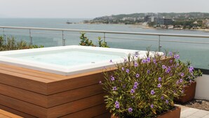 A wooden hot tub with a view of the sea and a cityscape in the background. - Stylish Oceanfront Condo w/ Jacuzzi, Pool & Gym (Bucerías)