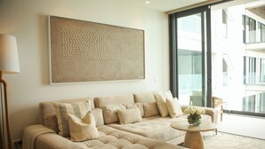 A modern living room with a large sectional sofa, a round coffee table, and a large abstract painting on the wall. - Stylish Oceanfront Condo w/ Jacuzzi, Pool & Gym (Bucerías)