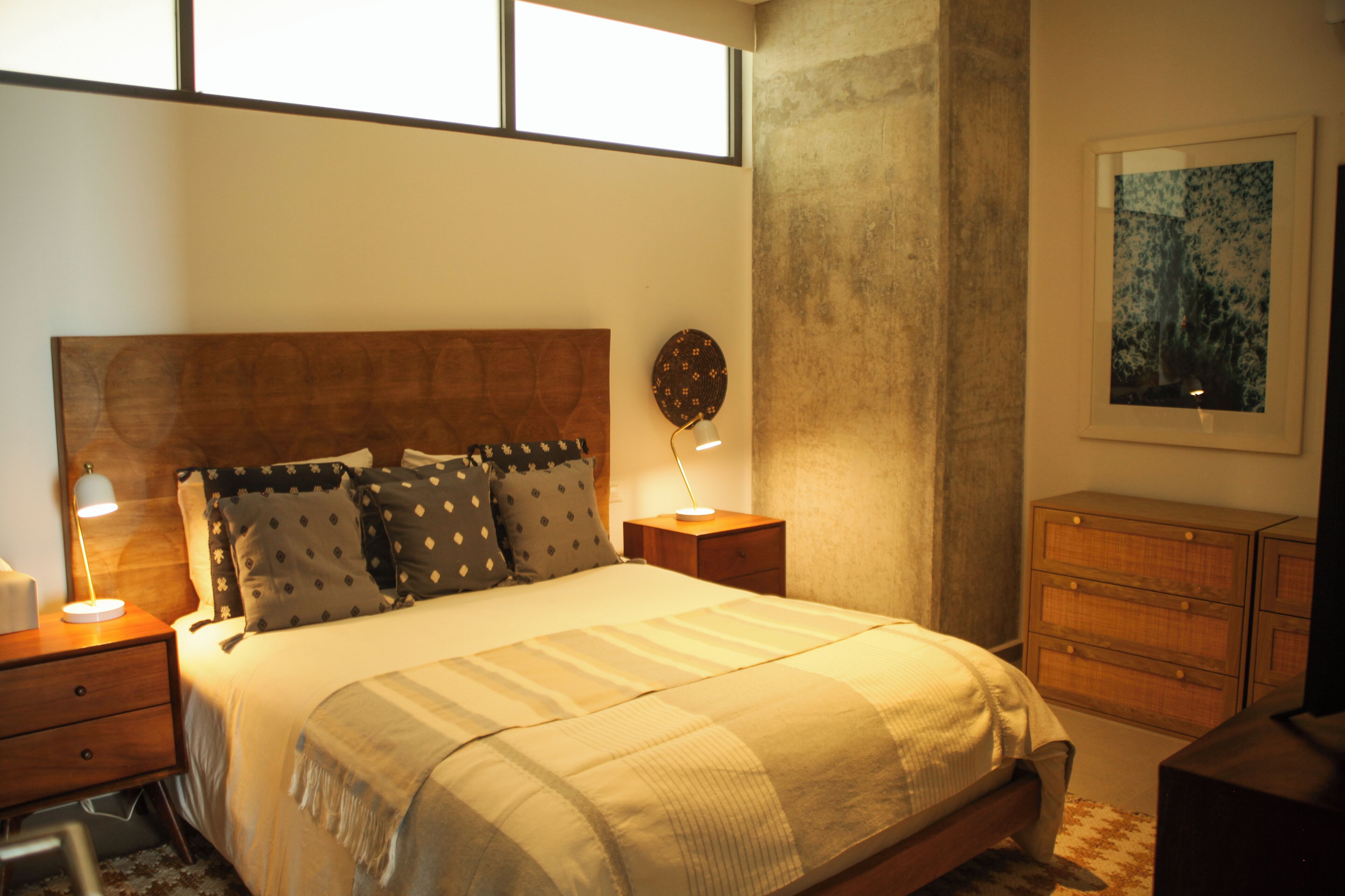A bedroom with a bed, nightstands, a dresser, and a window.
