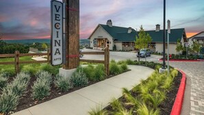 A sign for 'VECINA APTS 20915' with a view of a building and a sunset. - Landing | Modern 2BD, Game Room, Gym (San Antonio)