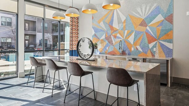 A modern kitchen with a large island, bar stools, pendant lights, and a colorful mosaic backsplash. - Landing | Amazing 1BD, Gym, Pool (Allen)