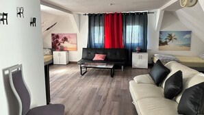 A modern living room with a black sofa, a white sofa, and a dining area with a white cabinet. - Pension Jasmin (Chemnitz)