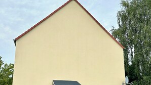 A single-story building with a flat roof, a small entrance with steps, and a satellite dish on the side. - Pension Jasmin (Chemnitz)