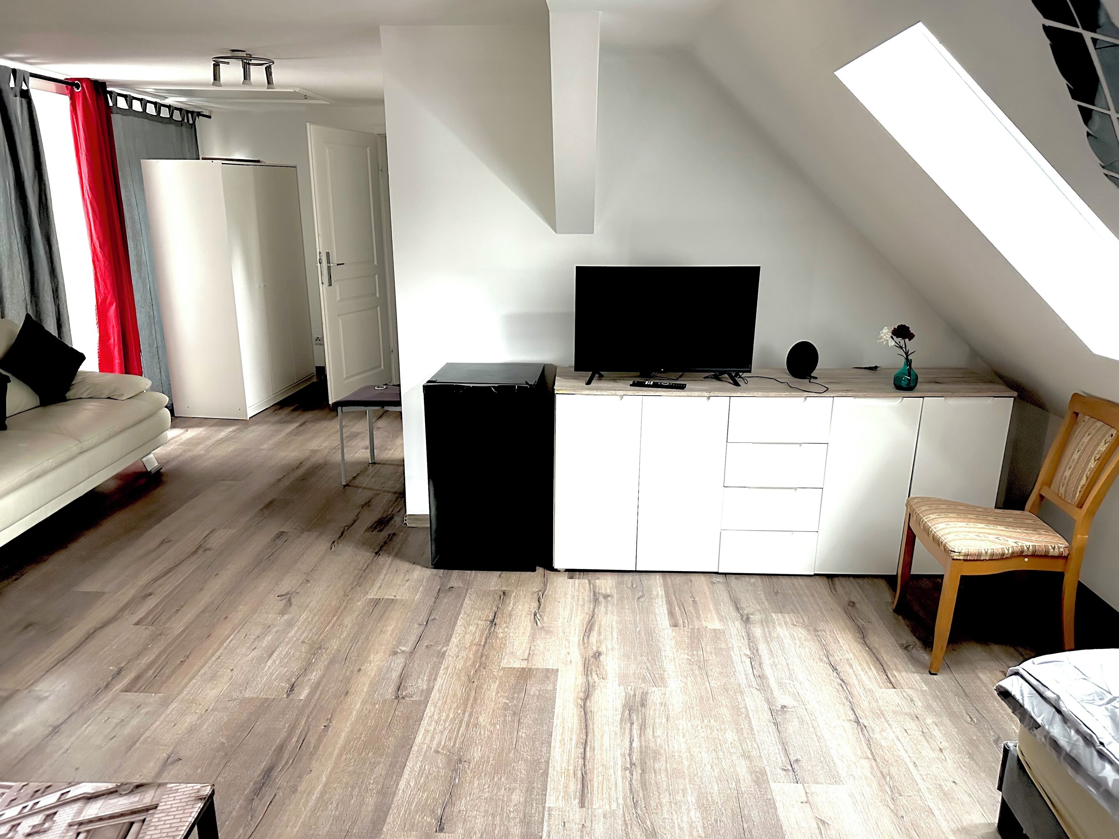 A compact living space with a sofa, a small table, a TV, and a chair.