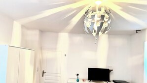 A room with a white wardrobe, a white dresser, a flat-screen TV, and a decorative globe light. - Pension Jasmin (Chemnitz)