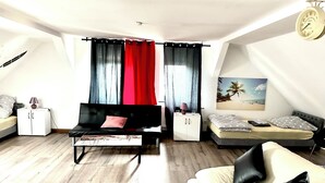 A modern living room with a sofa, a bed, a small cabinet, and a painting on the wall. - Pension Jasmin (Chemnitz)