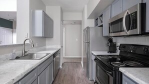 A modern kitchen with stainless steel appliances, a double sink, and light-colored cabinetry.