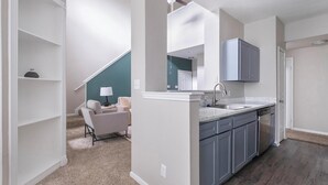 A modern kitchen with grey cabinets, a white countertop, and a built-in dishwasher.