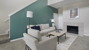Un salon avec un mur d’accent de couleur turquoise, un canapé, une table basse et une cheminée.