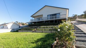 Une maison à deux étages dotée d’un balcon, d’un petit jardin et d’un escalier menant à l’étage supérieur.