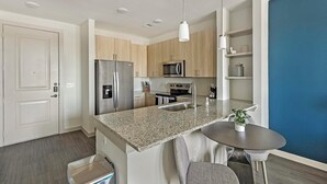 Eine moderne Küche mit Granit Arbeitsplatten, Edelstahlgeräten und einer eingebauten Mikrowelle.