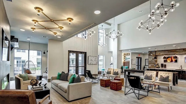 A spacious living area with a sofa set, a dining table, and a kitchen area.