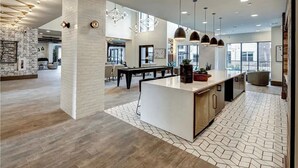 A spacious kitchen with a central island, pendant lighting, and a view of the dining area.